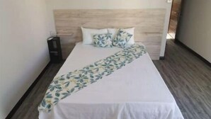 A neatly made bed with a floral bedspread, a bedside lamp, and a wooden headboard in a hotel room. - Splendid 4-bedrooms villa private pool near beach (Flic en Flac)