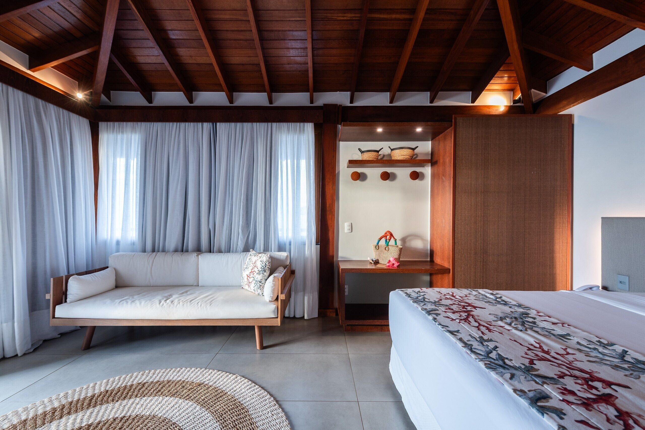 A modern room with a sofa, a bed, a desk, and a wooden ceiling.
