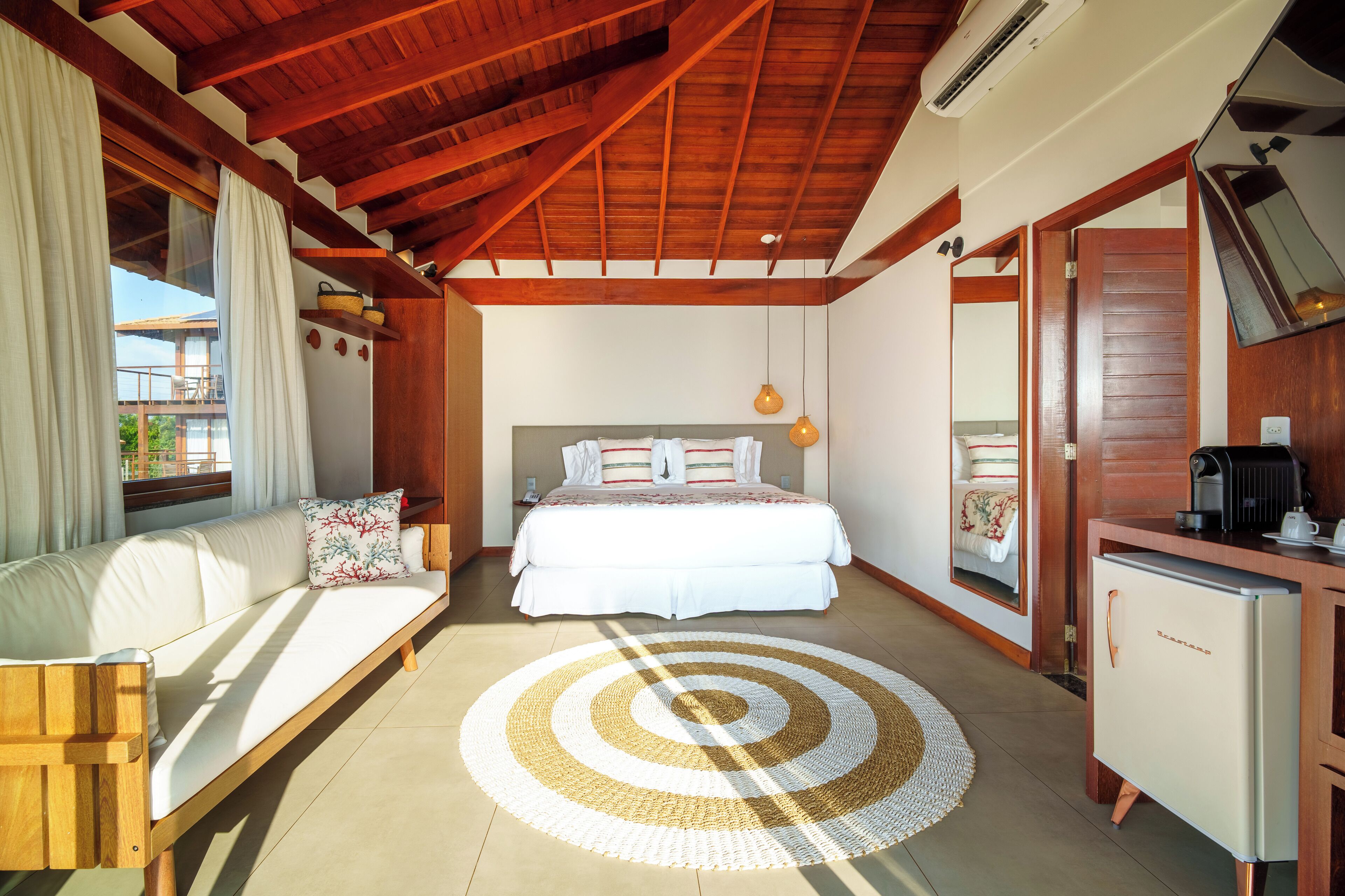 A bedroom with a bed, a sofa, a small kitchenette, and a large window.