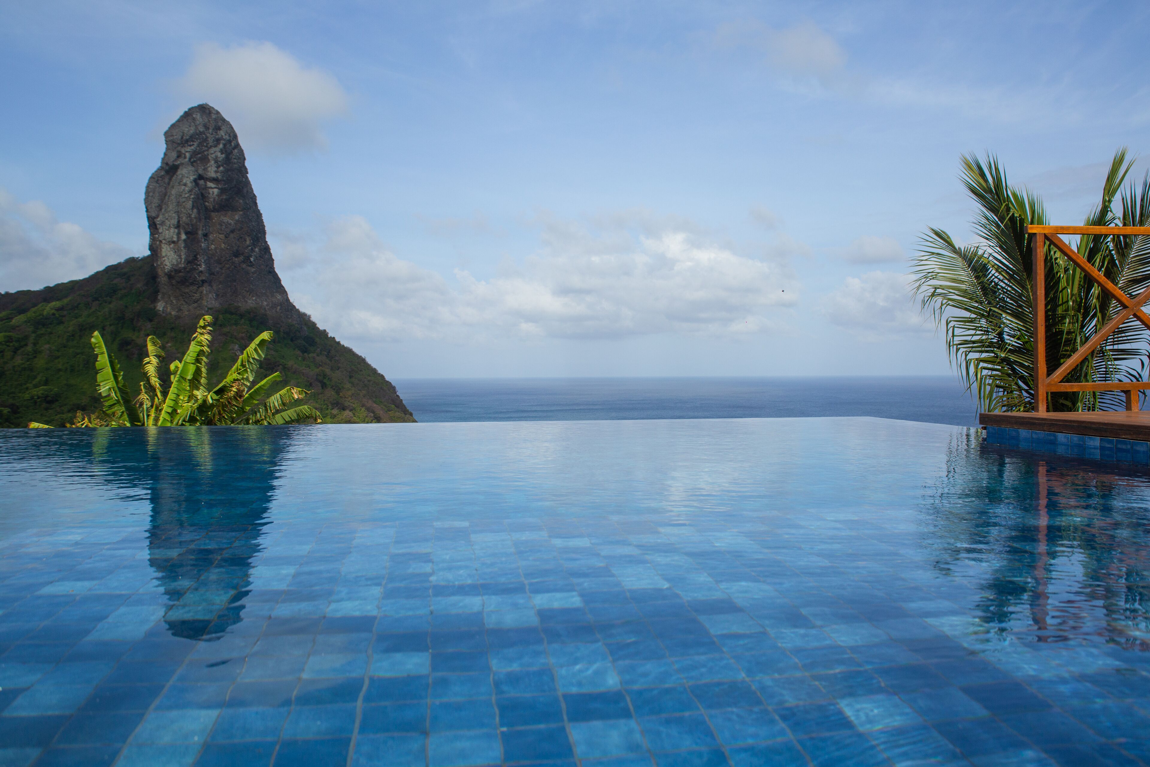 A infinity pool with a clear view of the ocean and a mountain in the background.