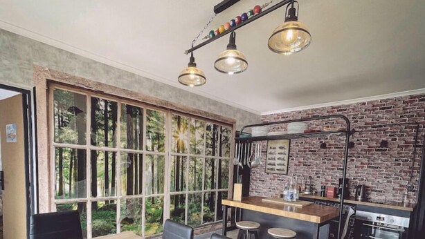 A modern dining area with a large wooden table, black chairs, and a bar area with stools.