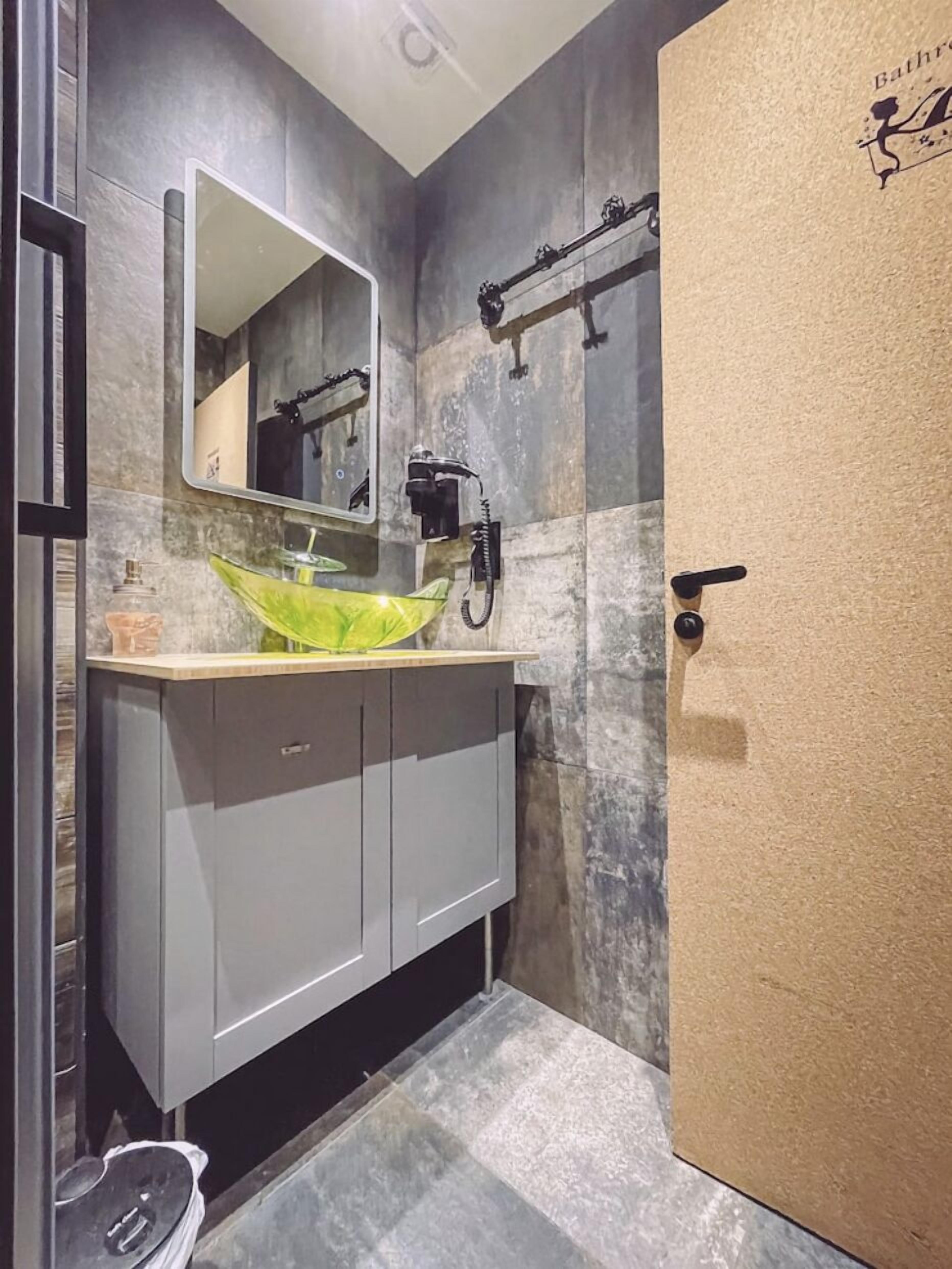 Un bagno con uno specchio grande, un lavandino verde e un porta asciugamani.