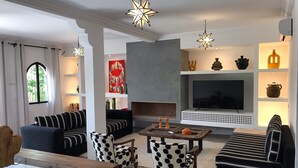 A modern living room with a fireplace, a TV, and various decorative items on shelves. - Villa Piscine Marrakech (Marrakech)