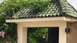 A doorway leading to a swimming pool area with a tiled roof and greenery. - Villa Piscine Marrakech (Marrakech)