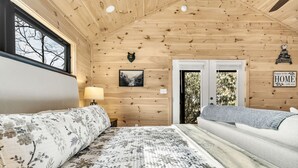 Een slaapkamer in een houten hutje met twee bedden, een berenhoofd decoratie, een ingelijste foto en een bordje met de tekst 'blij om thuis te zijn'.