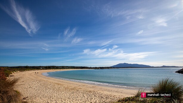 Ein Strand mit blauem Himmel und ruhiger See.