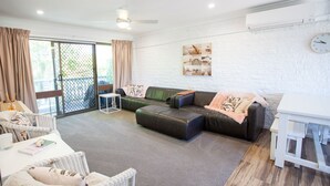 Ein modernes Wohnzimmer mit einem Ecksofa, einem kleinen Tisch und einer weißen Wand mit einer Uhr.