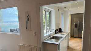 Een moderne keuken met uitzicht op zee, een inbouwspoelbak en een koelkast.