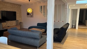 Een moderne woonkamer met een flatscreen televisie, een houten salontafel en een blauwe bank.