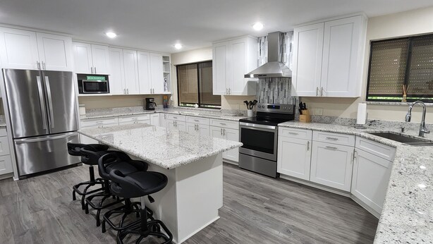 A modern kitchen with white cabinets, stainless steel appliances, a granite countertop, and a bar stool area. - Heated Pool, Shopping, Restaurants, Beach's, Southern Exposure (Naples)