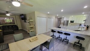 A modern kitchen with a central island, bar stools, and a dining area with a table and chairs. - Heated Pool, Shopping, Restaurants, Beach's, Southern Exposure (Naples)
