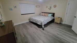 A bedroom with a bed, a ceiling fan, a nightstand, and a door. - Heated Pool, Shopping, Restaurants, Beach's, Southern Exposure (Naples)