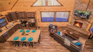 A spacious cabin interior with a kitchen, dining area, and a fireplace. - To Infinity And Beyond: Indoor-Pool, VIEWS, Theater, Game Room, Hot Tub, WiFi, close to Attractions! (Sevierville)