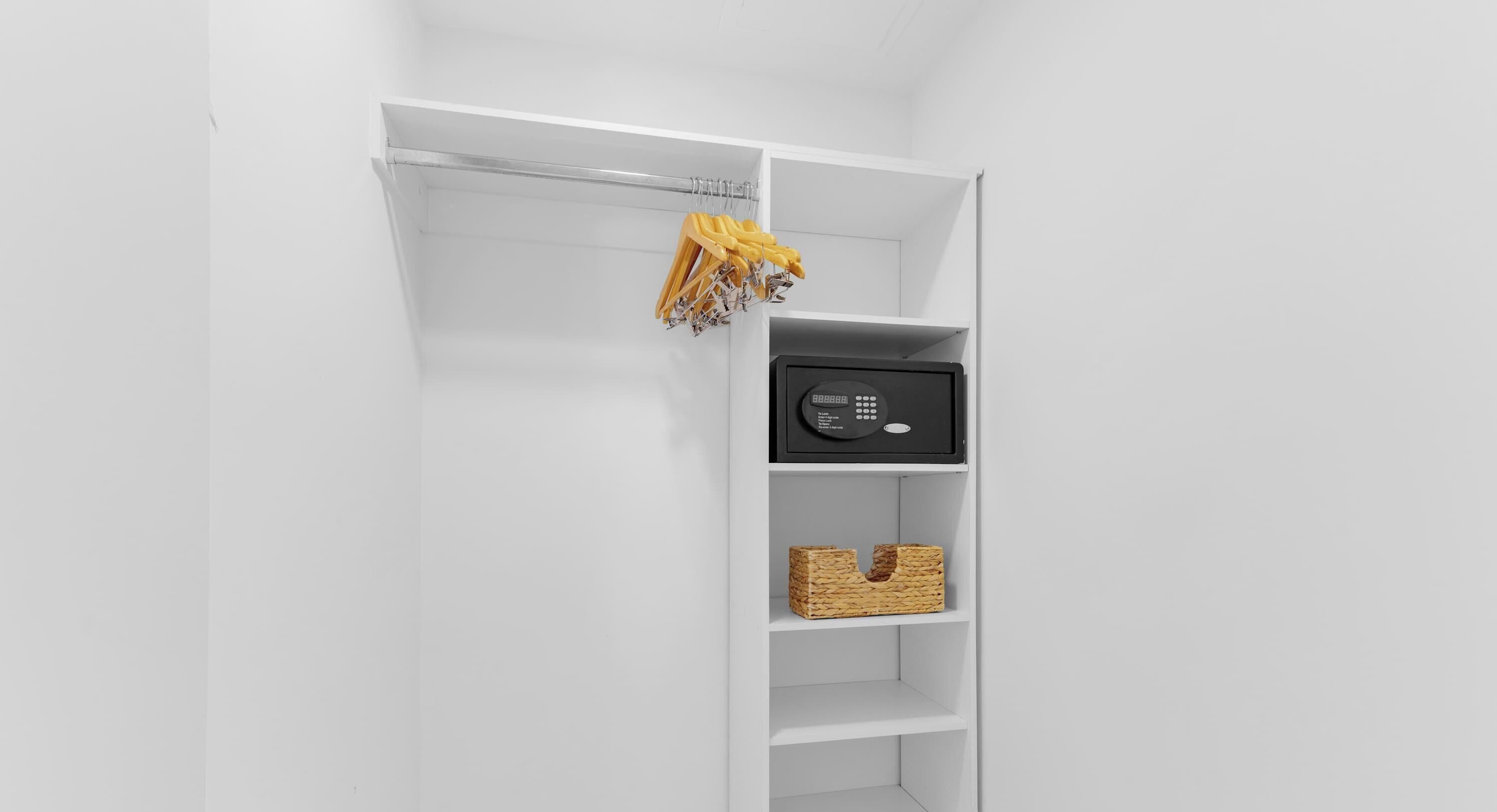 Un placard blanc avec des étagères, une tringle et un appareil électronique noir.