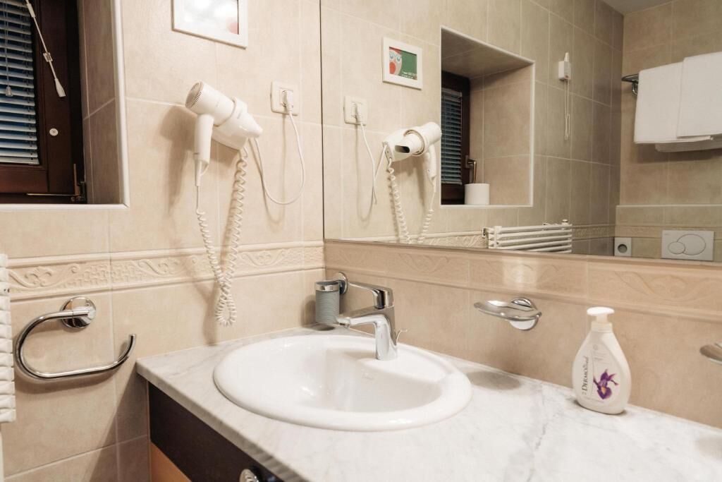 Une salle de bain équipée d’un lavabo, de deux sèche-cheveux, d’un miroir et d’un porte-serviettes.