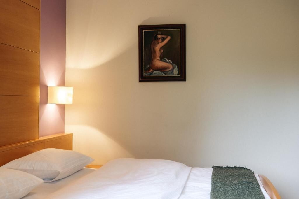 Une chambre d’hôtel avec un lit, des oreillers, un tableau accroché au mur et une lampe de chevet.