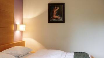Une chambre d’hôtel avec un lit, des oreillers, un tableau accroché au mur et une lampe de chevet.