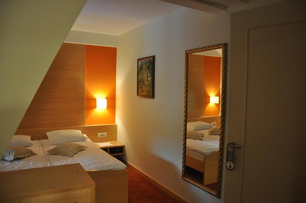 Une chambre d’hôtel avec un lit, une table de chevet et un miroir qui reflète la pièce.