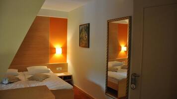 Een hotelkamer met een bed, nachtkastje en een spiegel die de kamer weerspiegelt.