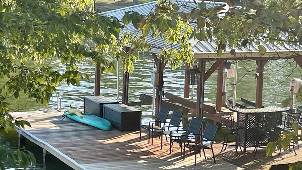 Una terraza de madera con mobiliario exterior, una piscina pequeña y un espacio cubierto con una mesa y sillas.