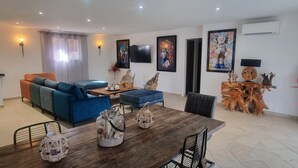 Una sala moderna con un sofá azul, una mesa de comedor de madera y elementos decorativos.