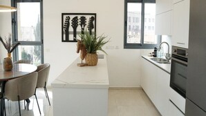 Una cocina moderna con armarios blancos, una isla de mármol y una planta en maceta.