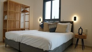 Un dormitorio con cama, armario, ventana y mesita de noche.