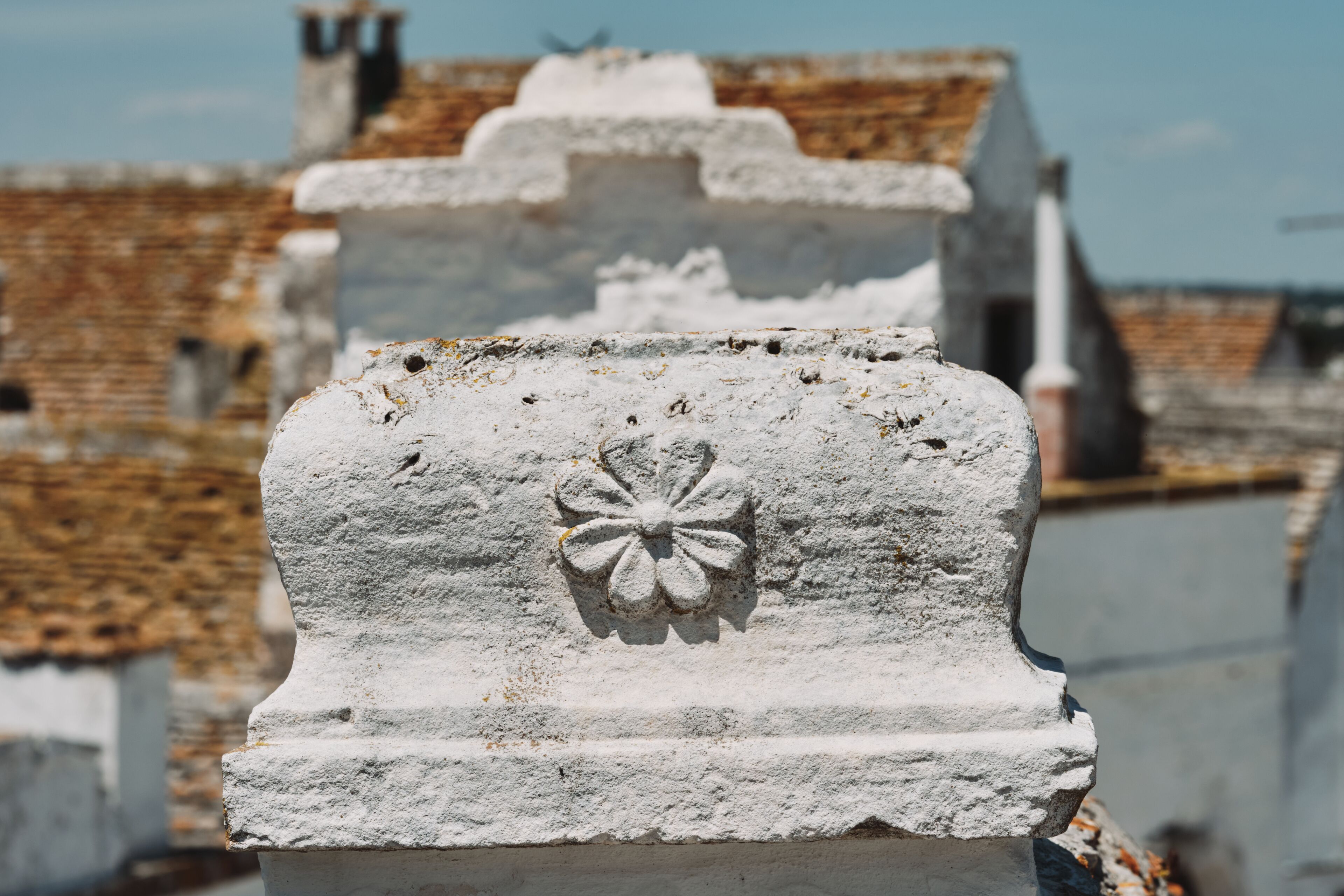 A stone headstone with a floral design, part of a larger cemetery structure.