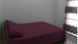 A small, single-bed room with a wooden headboard, a plain wall, and a window with curtains. - 1F,F1,U5 Apartment (Athurugiriya)