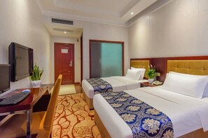 A hotel room with two beds, a desk with a computer, a TV, and a small plant. - Youjia Hotel (Bijie)