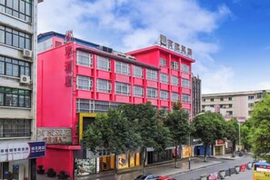 A multi-story building with a prominent red facade, multiple windows, and a visible entrance. - Youjia Hotel (Bijie)