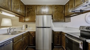 A kitchen with wooden cabinets, stainless steel appliances, a dishwasher, and a stove. - Rosewood Townhouse (Columbia)