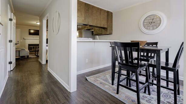 A modern kitchen with wooden cabinets, a dining table with chairs, and a patterned rug. - Rosewood Townhouse (Columbia)
