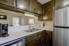 Una cocina con armarios de madera, electrodomésticos de acero inoxidable, una cafetera y un fregadero.