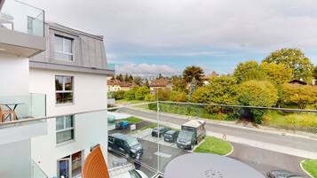A modern apartment with a balcony overlooking a street and greenery.