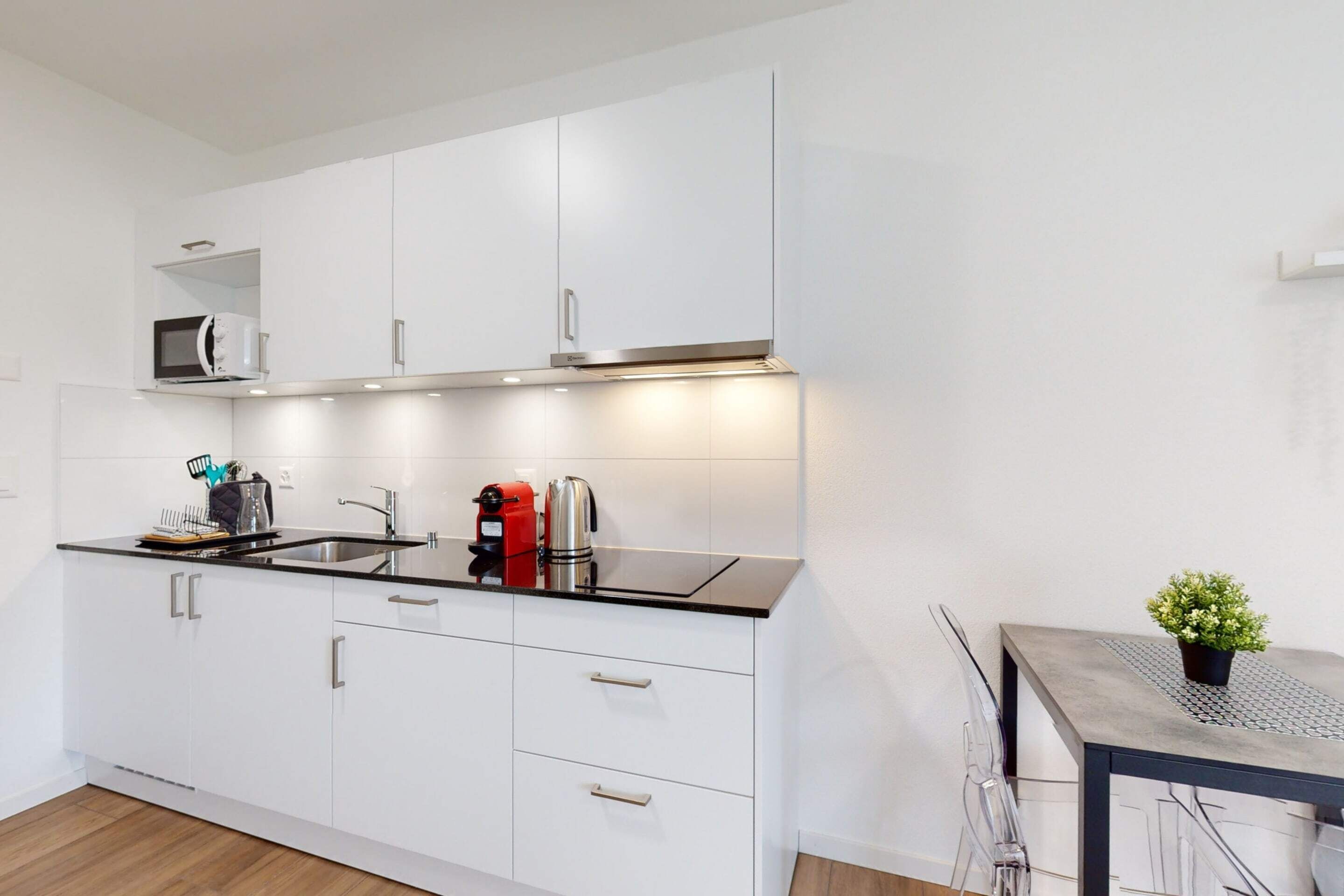 A modern kitchen with white cabinets, a black countertop, and stainless steel appliances.