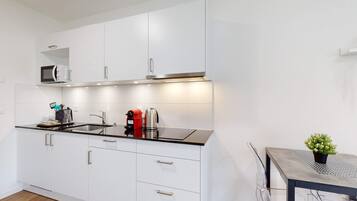 A modern kitchen with white cabinets, a black countertop, and stainless steel appliances.