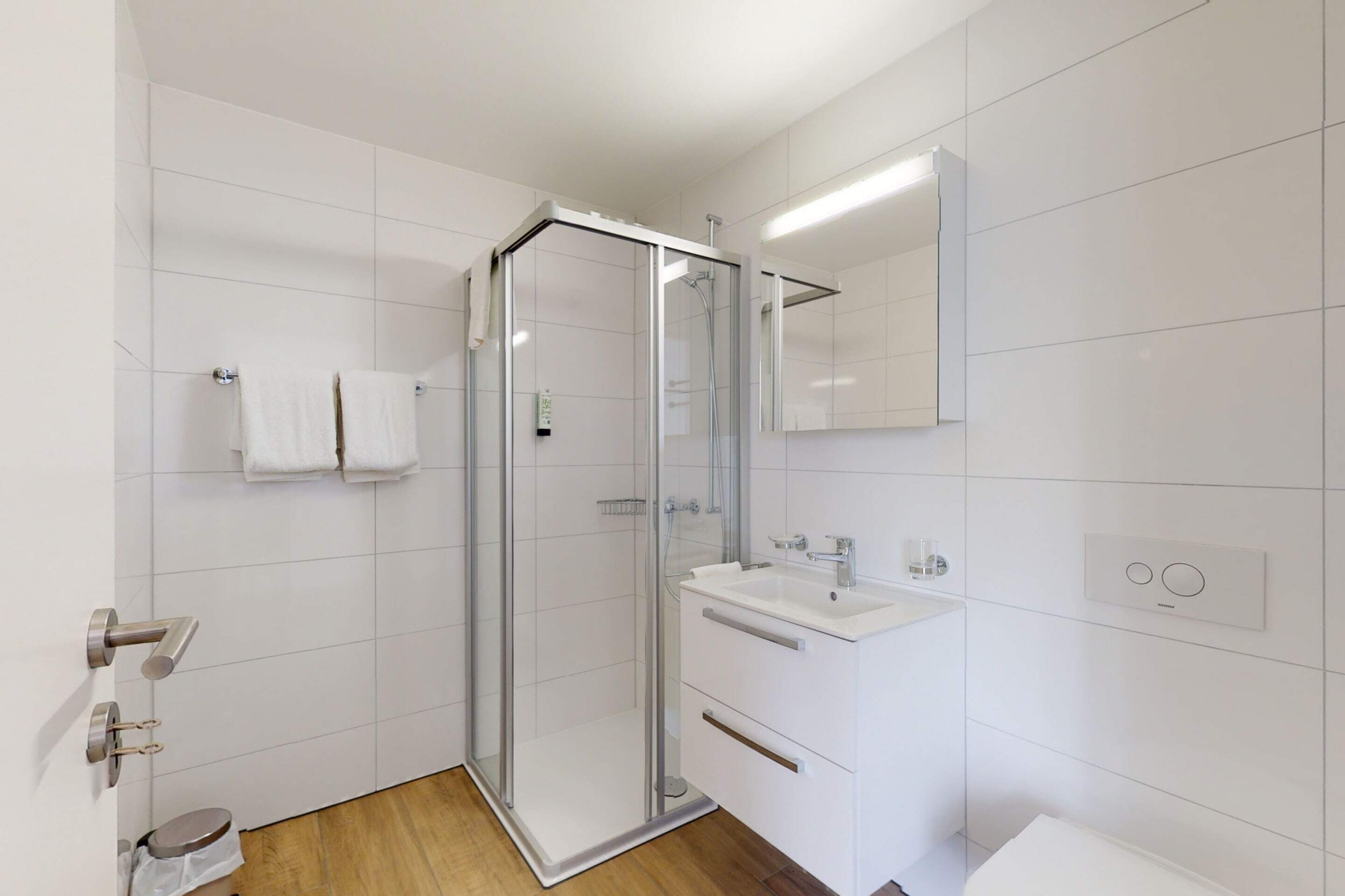 Un baño moderno con cabina de ducha de vidrio, un lavabo blanco y un espejo encima.