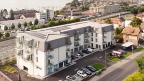 A modern building with multiple floors, balconies, and a parking area. - Lodges Hotel Morges (Morges)