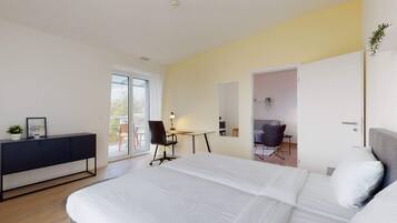 Een moderne hotelkamer met een groot bed, een bureau en een stoel. Er is een schuifglazen deur die leidt naar een balkon.