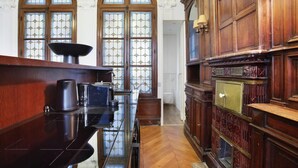 Una habitación con un escritorio de madera pulida, una amplia estantería y un ventanal con vitrales.