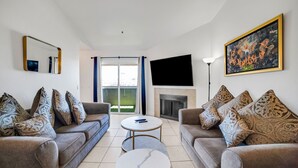 Ein Wohnzimmer mit zwei Sofas, einem Couchtisch, einem Flachbildfernseher und einem Kamin.