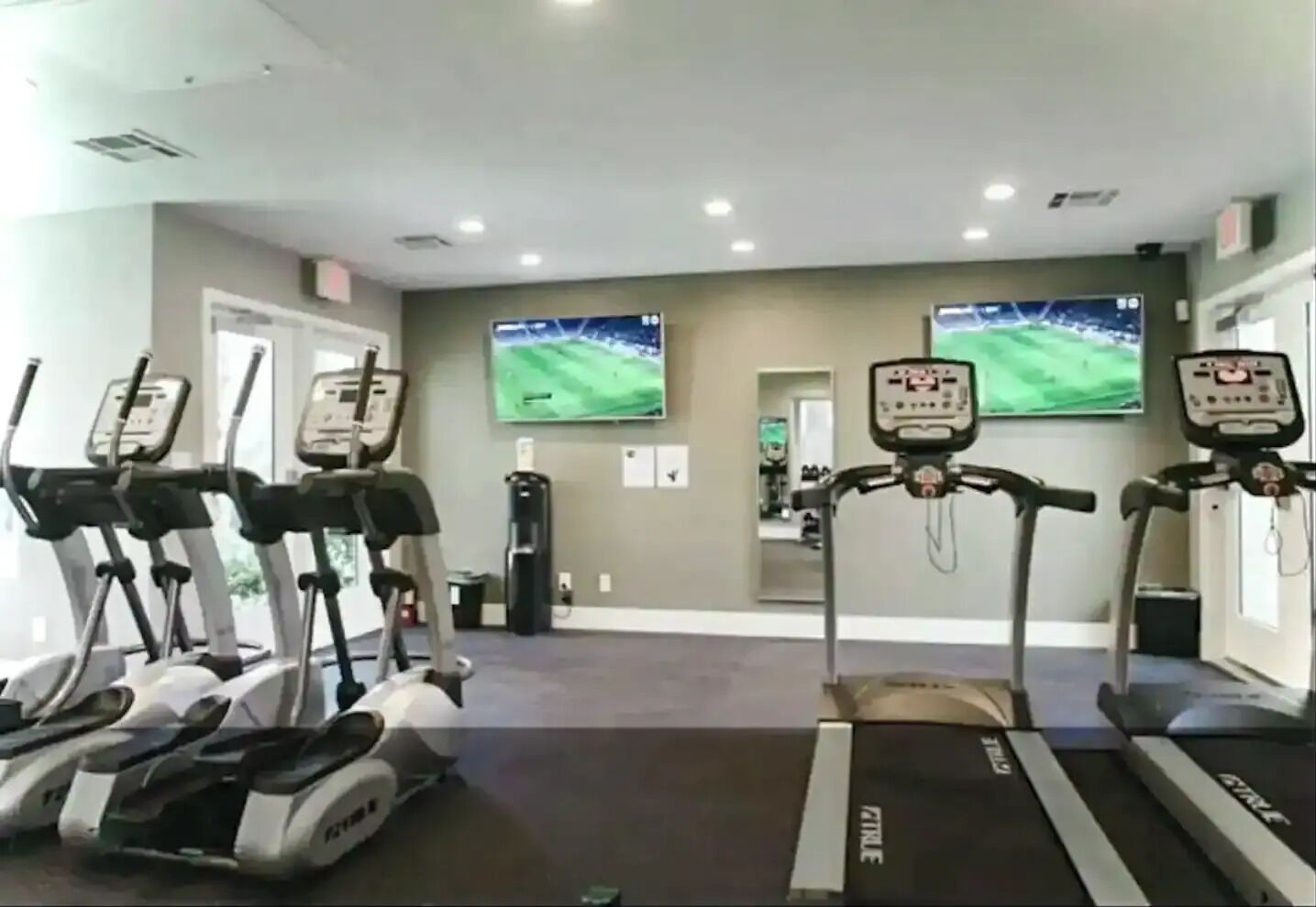 A gym with treadmills, stationary bikes, and a punching bag.
