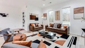 A modern living room with two leather sofas, a coffee table, and a grey armchair. - Modern Luxury In The City at Havilah Estates (Atlanta)