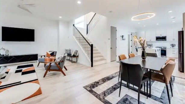 A modern living room with a staircase, a dining area, and a kitchen. - Modern Luxury In The City at Havilah Estates (Atlanta)