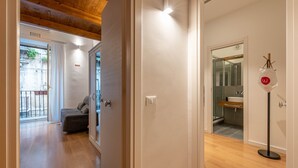 A hallway with a wooden ceiling, a sofa, a glass door leading outside, and a bathroom with a sink and mirror. - Casa Abbanniata a Ballarò by Wonderful Italy (Palermo)