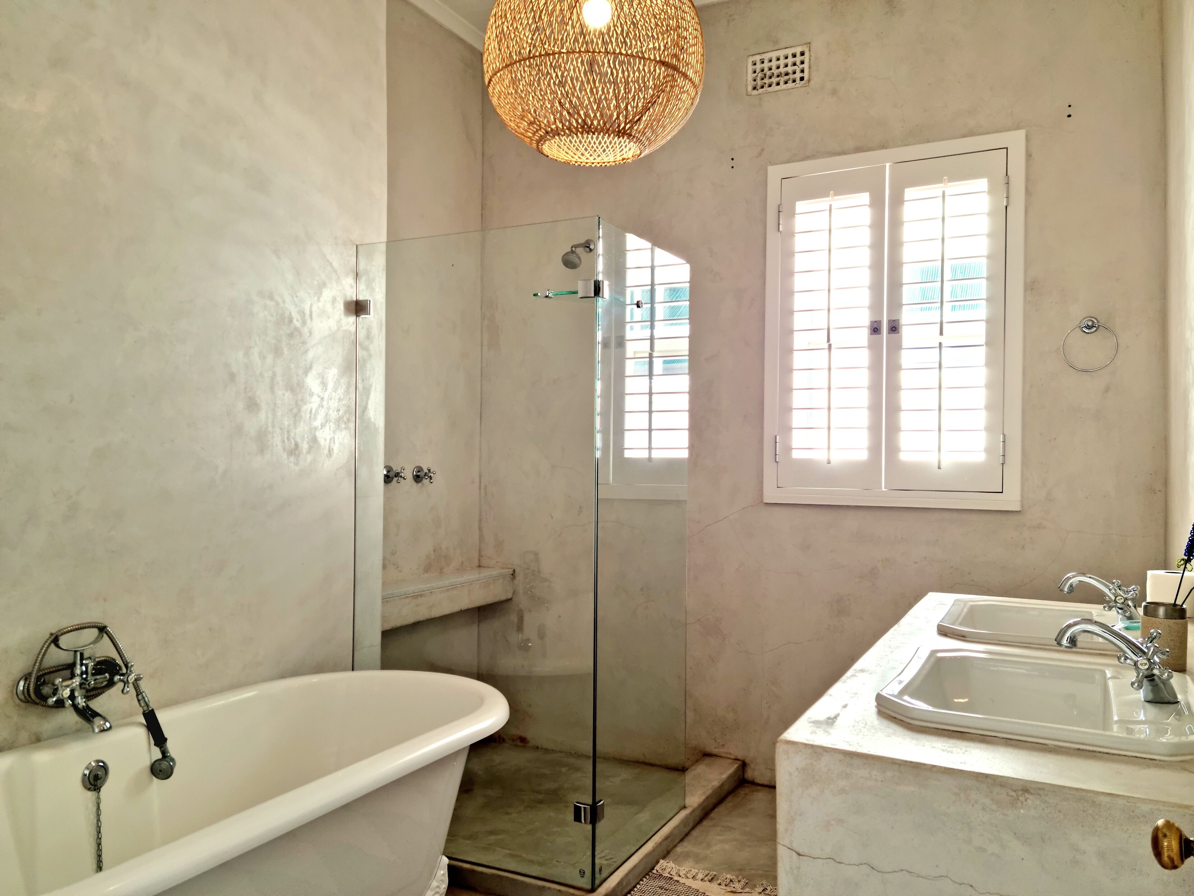 Un baño con ducha envuelta en vidrio, una bañera independiente y un lavabo con espejo.