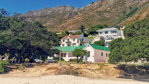 Zona residencial amb cases, un primer pla sorrenc i un paisatge de muntanyes al fons.
