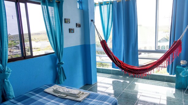 Um quarto com cama, rede e vista para o exterior.