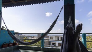 Uma rede numa varanda com vista para edifícios e um céu claro.